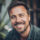 Homme souriant avec barbe et cheveux courts.