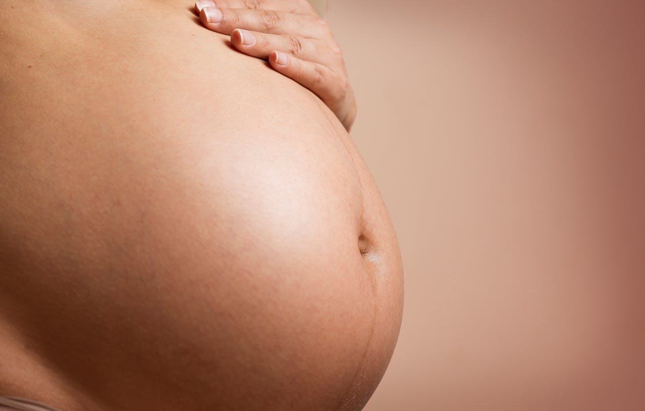 An intimate close-up of a pregnant woman's abdomen, highlighting maternity and parenthood.